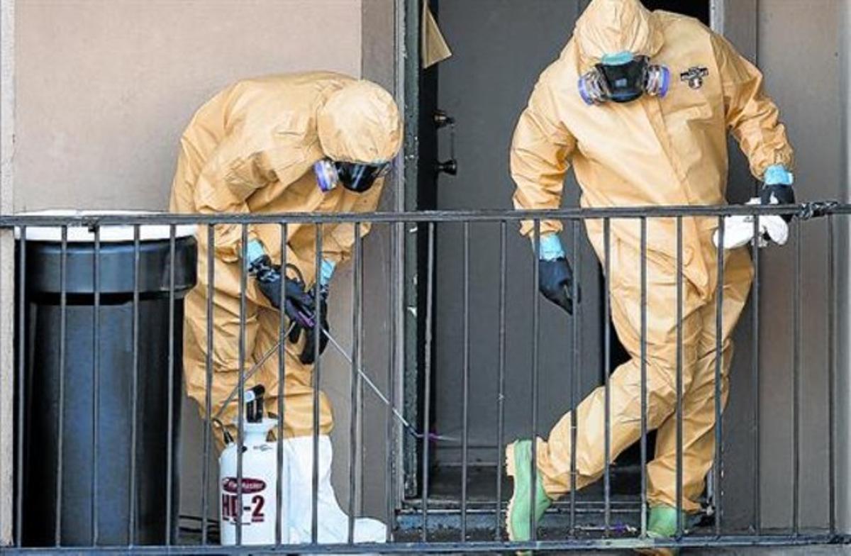 Dos treballadors es netegen els vestits després de buidar el pis de l’home a qui es va diagnosticar Ebola a Dallas.
