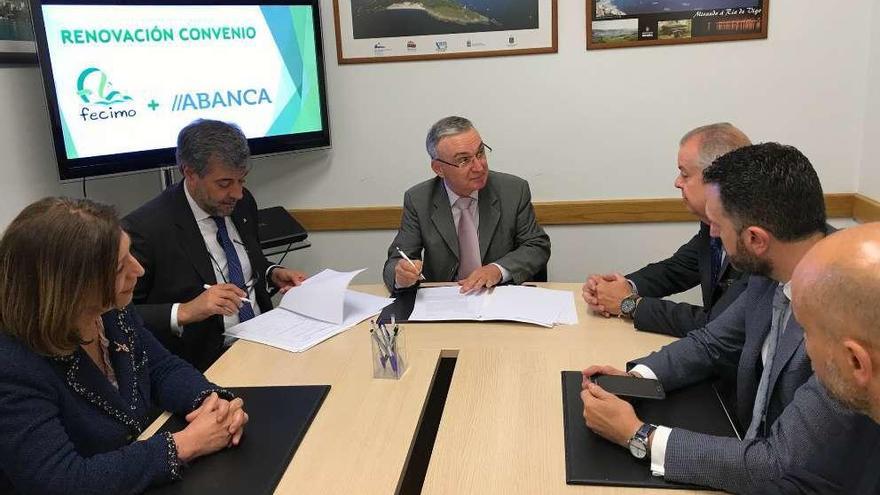 El presidente de Fecimo, Xosé Bangueses (al frente), y el director territorial de Abanca en Vigo, Jorge Martínez, firman el convenio de colaboración, ayer en Cangas. // G.N.