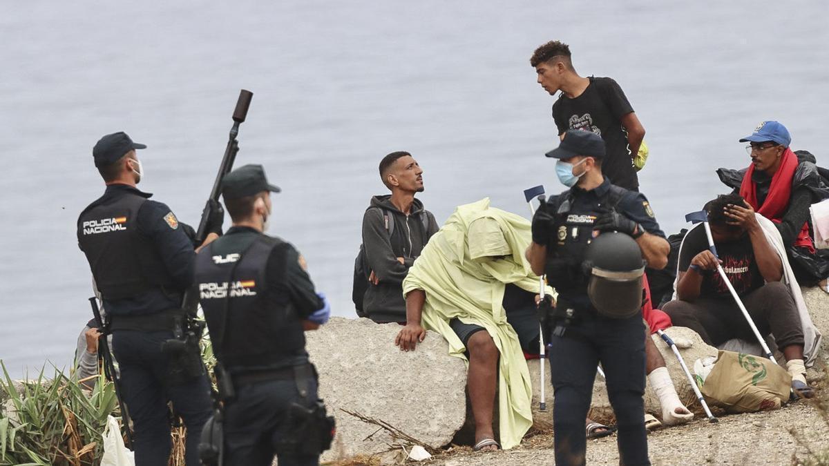 La policía vigila a inmigrantes que continúan viviendo en la playa del Trampolín de Ceuta, este viernes.