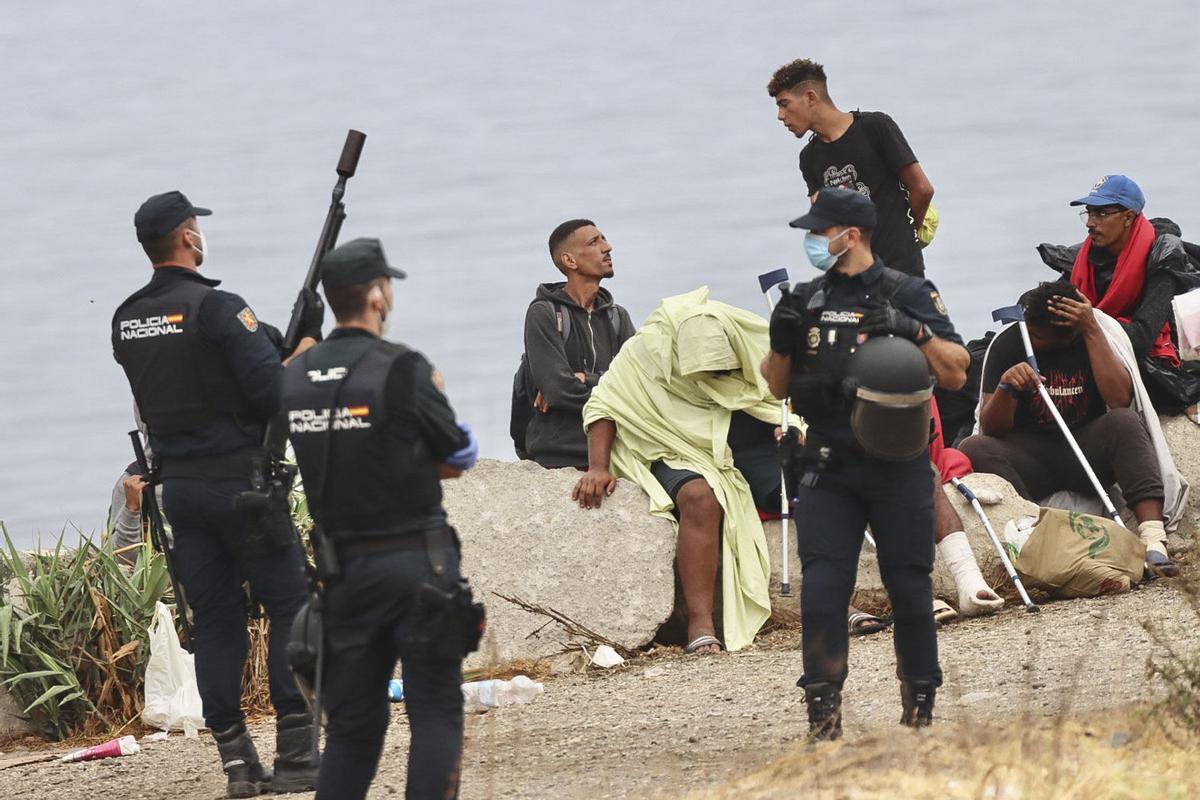 La policía vigila a inmigrantes que continúan viviendo en la playa del Trampolín de Ceuta, este viernes.