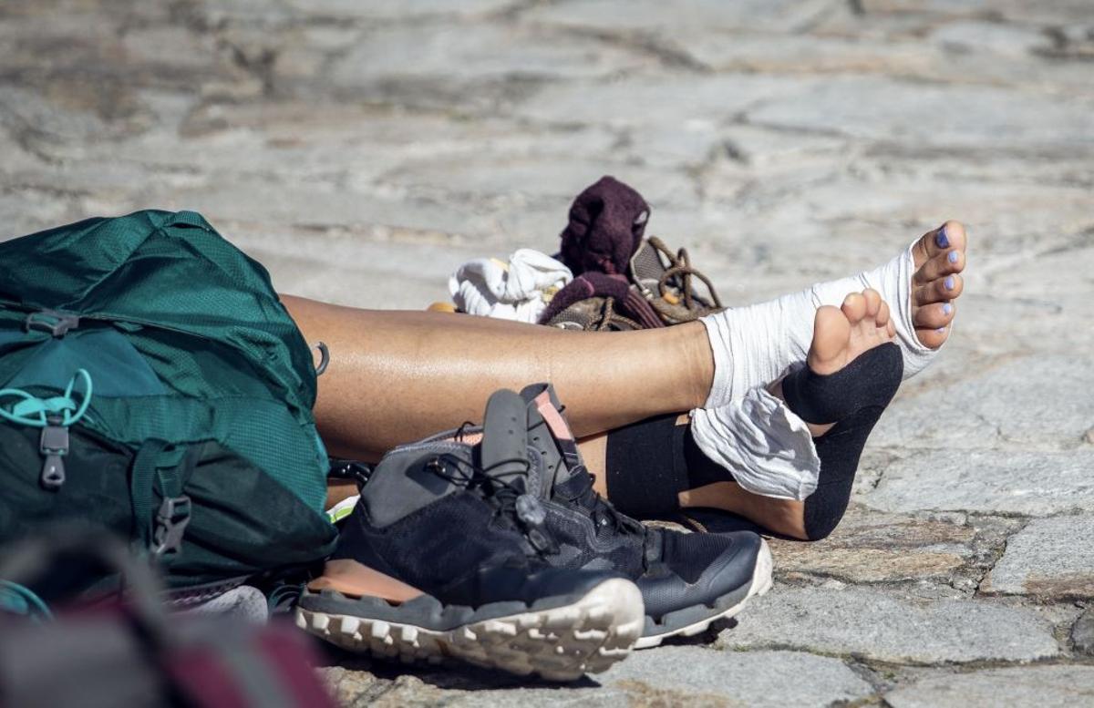 Un peregrino descansas sus maltrechos pies a su llegada al Obradoiro