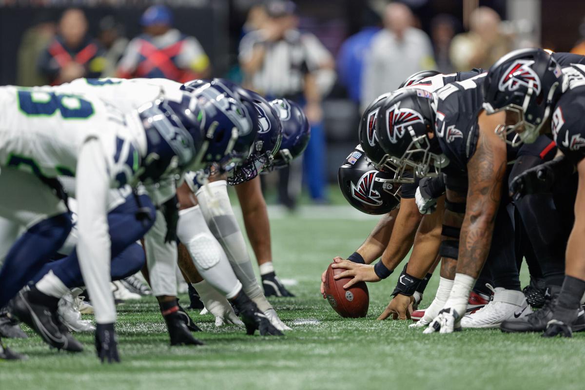 La ofensiva de los Seattle Seahawks, con camiseta y pantalón blancos, se alinea contra la defensa de los Atlanta Falcons durante partido de la NFL