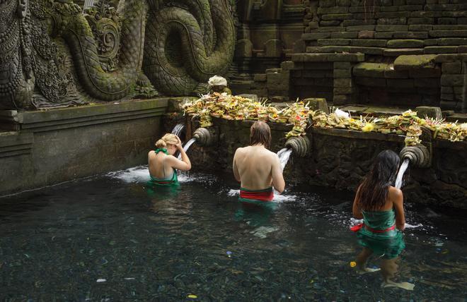 Personas bañándose en las aguas sagradas de Tirta Empul