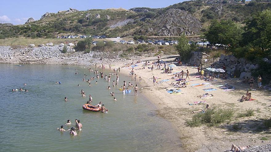 Un grupo de personas disfrutan de la playa artificial de Ricobayo.