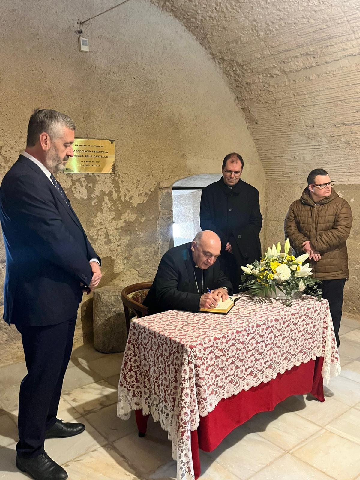 El arzobispo, al firmar en el libro de honor, bajo la mirada del alcalde, entre otros.