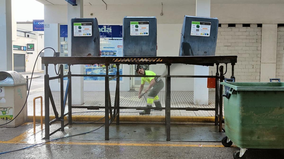 Un operario de La Pública limpia el soporte de unos contenedores de basura soterrados.