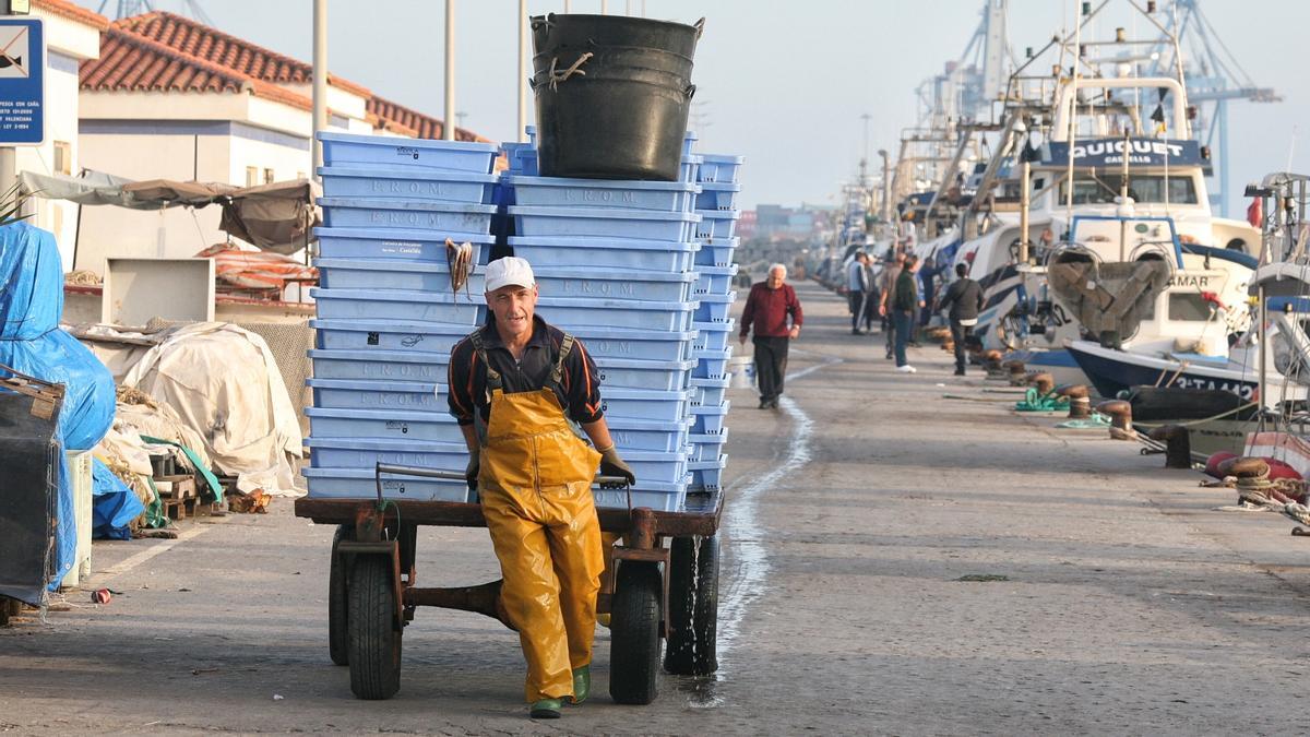 Un marinero del Grau transporta pescado desde el barco a la lonja.