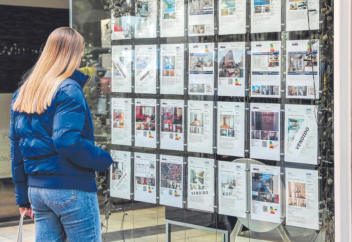 Una persona contempla el escaparate de una inmobiliaria.