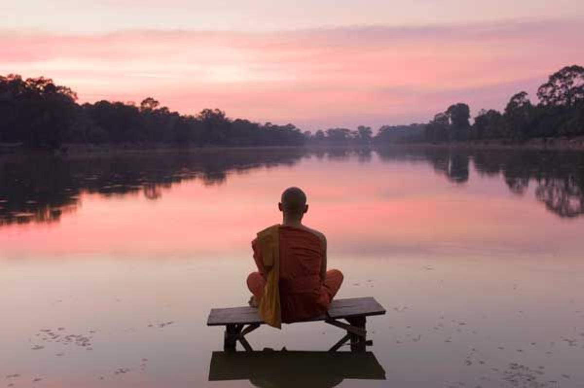 Un monje budista medita encima de una plataforma sobre el lago de Angkor Wat.