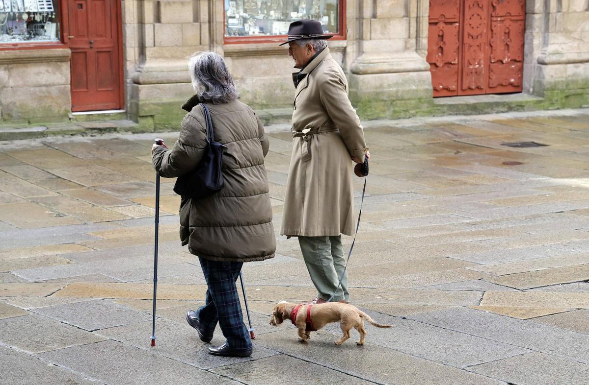 Dos personas pasean con su perro por la Praza de Praterías de Santiago