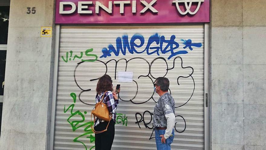 Dos afectats davant la persiana abaixada de la clínica Dentix de Girona, ahir.
