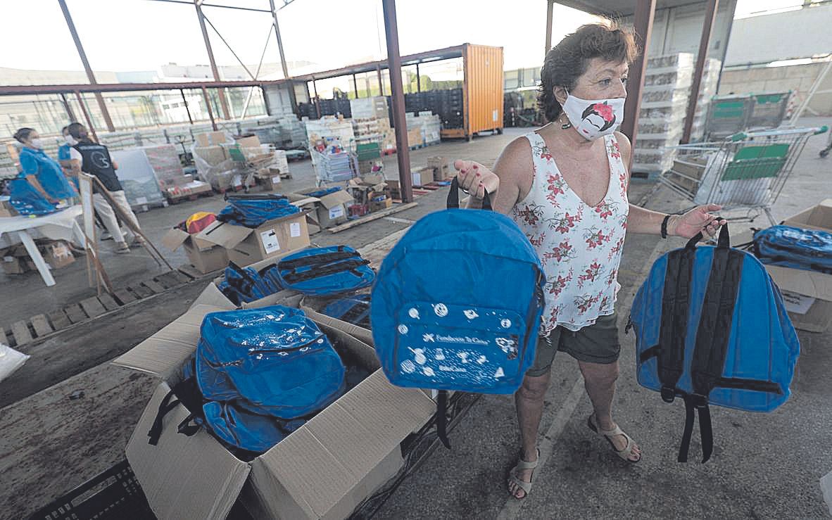 Una voluntaria con mochilas nuevas donadas para entregar a los niños.