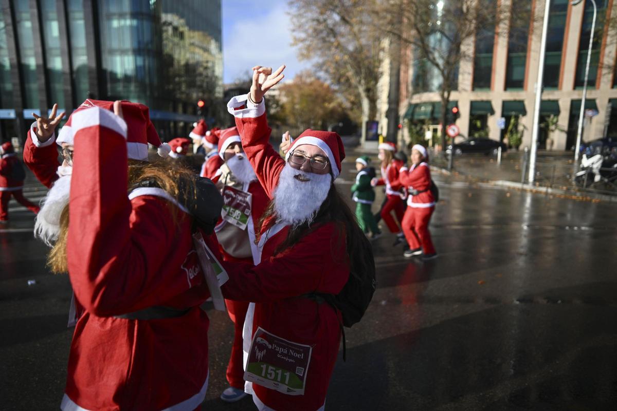 Participantes de todas las edades recorren el centro de Madrid vestidos de papá noeles durante la 14ª edición de la Carrera de Papá Noel, este domingo en Madrid.