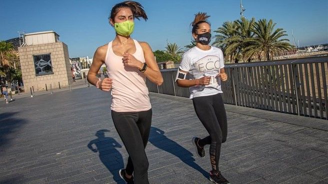 Dos chicas corren con mascarilla por el paseo Marítim de Barcelona.