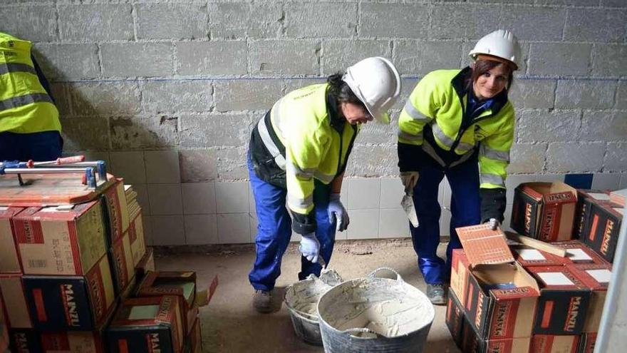 Tres alumnos realizando la reforma de los vestuarios del pabellón de La Rosaleda.