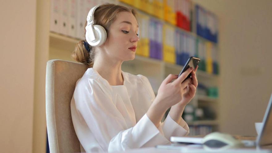 Una joven mira el móvil mientras escucha música