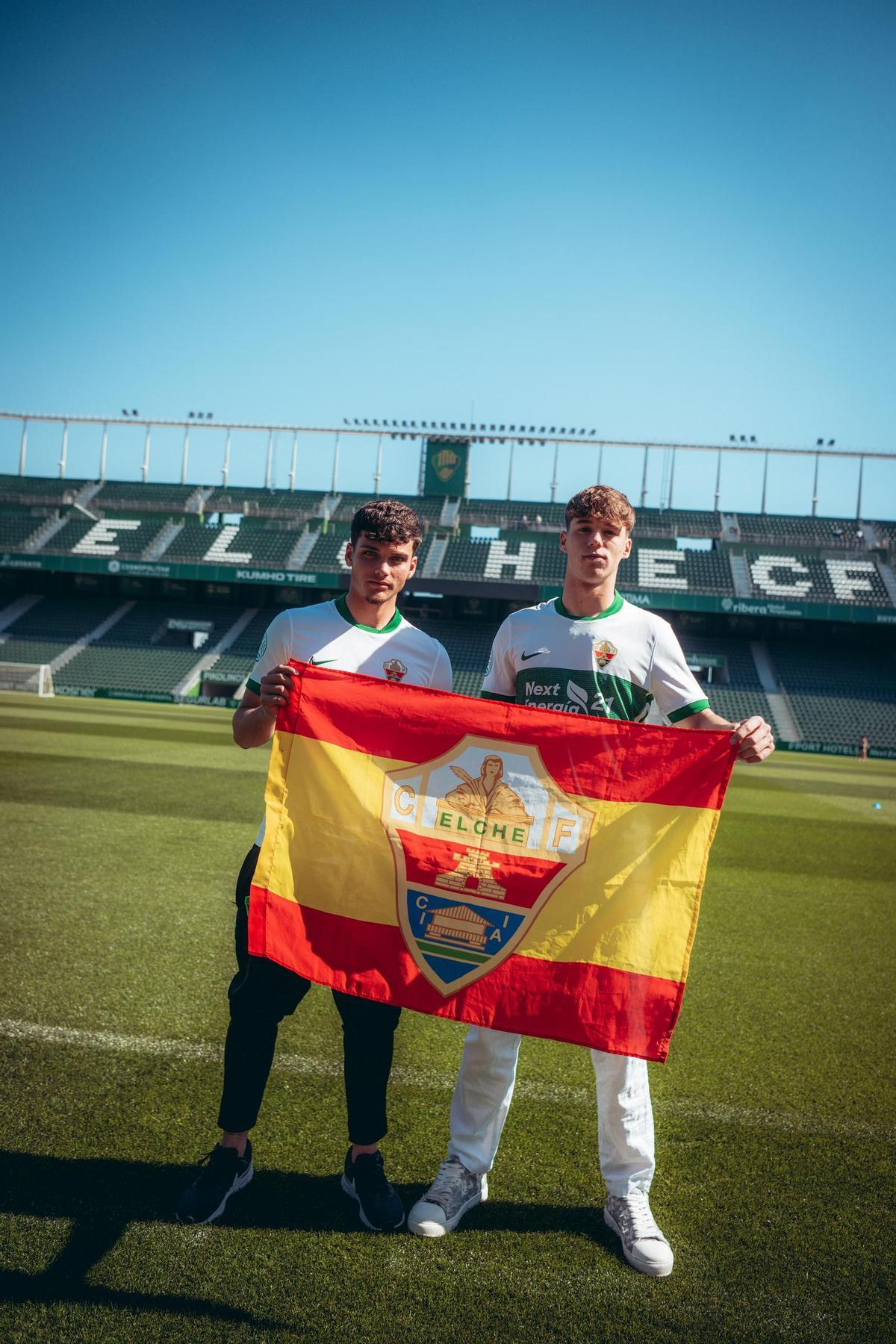 Álex Herráiz, lateral diestro, y David Hernández, defensa central, posan con una bandera de España con el escudo del Elche con motivo de su convocatoria.