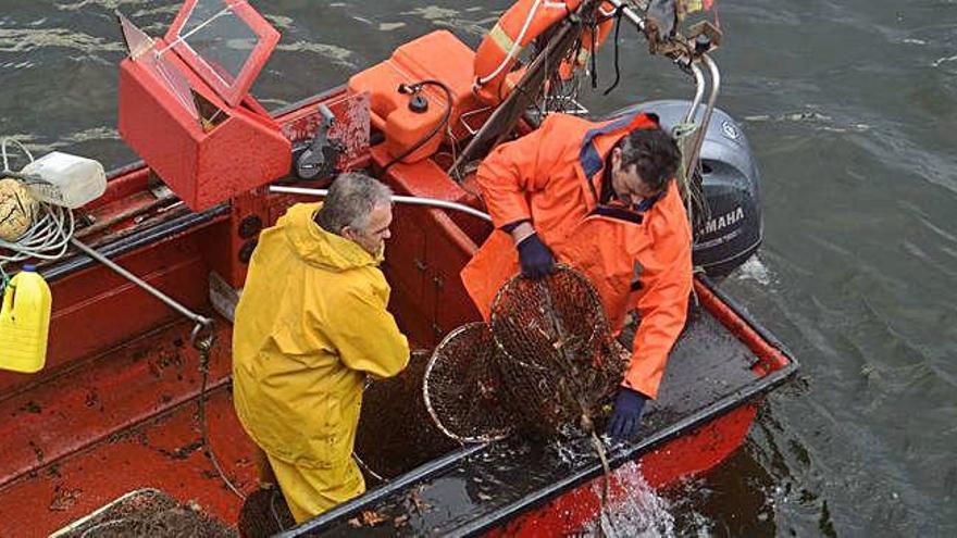 Dos pescadores recogen los aparejos durante una jornada de trabajo .