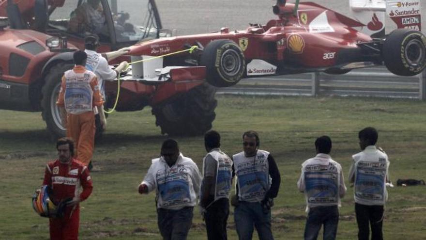 Lewis Hamilton acelera su monoplaza mientras una grúa retira el Ferrari de Fernando Alonso.