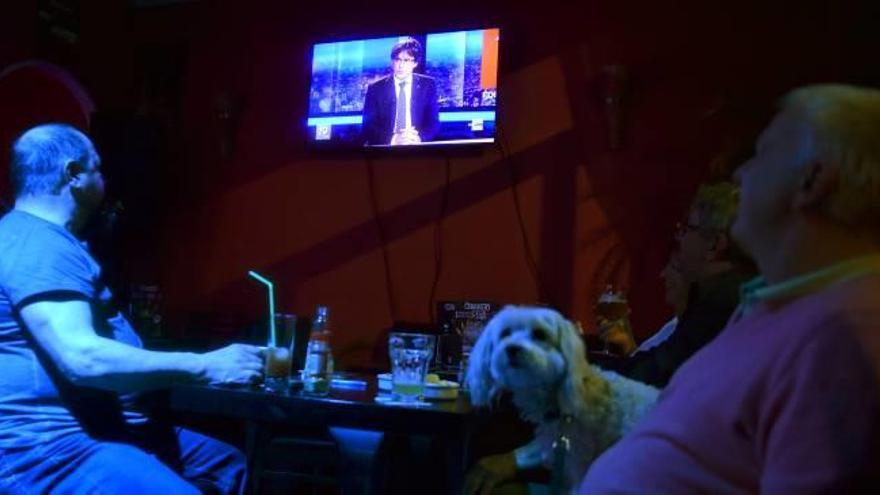Dues persones miren l&#039;entrevista a Puigdemont en un bar de Brussel·les.