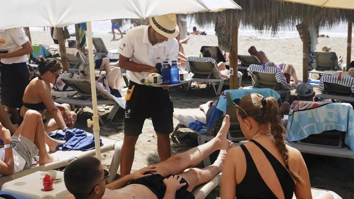 Un camarero atiende a los clientes en las hamacas de un chiringuito de Málaga.