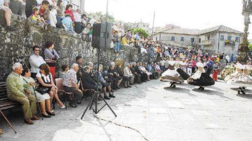 Gaiteiros e bailarinas agasallaron ás persoas maiores no adro parroquial, ó pé do cruceiro. / gonzalo nÚñez