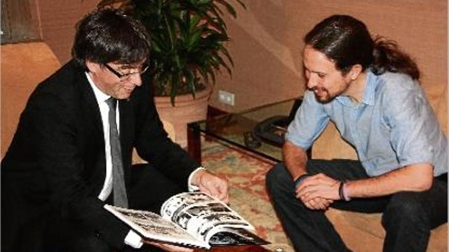 Carles Puigdemont fulleja el llibre que va regalar al líder de Podem, Pablo Iglesias, abans de la reunió.