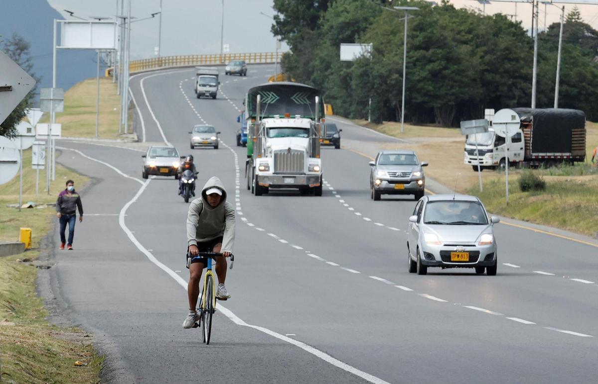 Un ciclista circula por el arcén de una carretera.