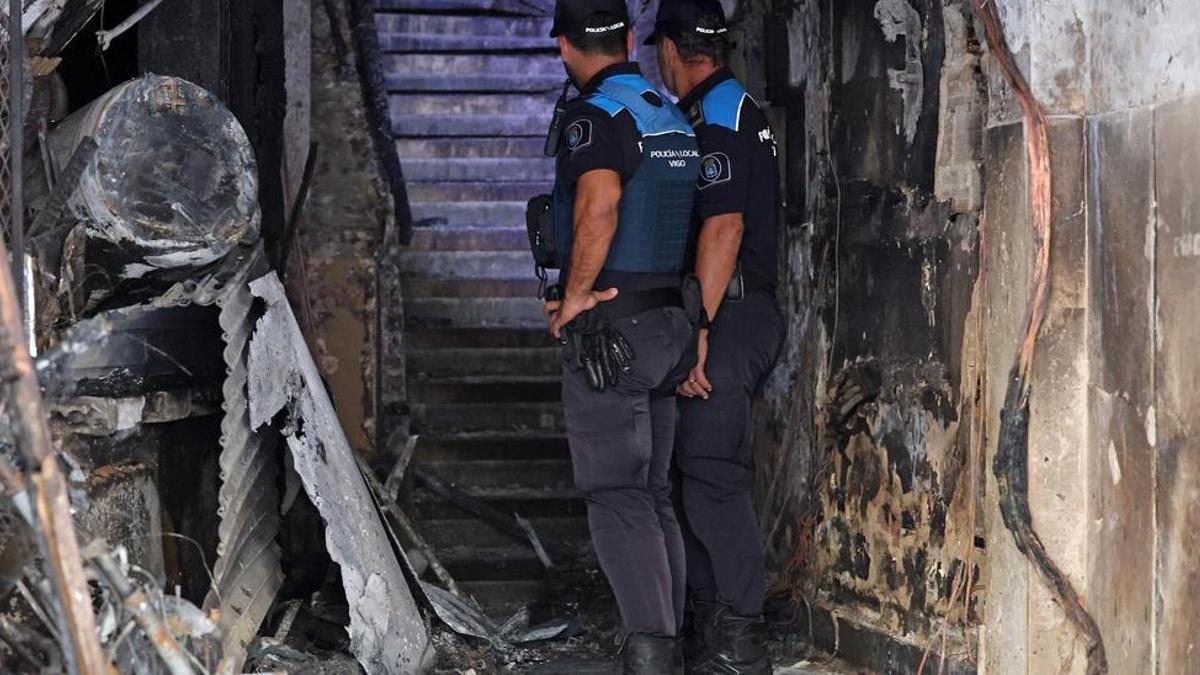 Dos agentes en el portal del edificio incendiado en la calle Alfonso