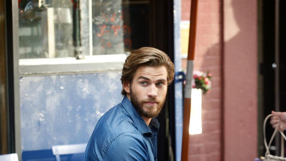 Liam Hemsworth sentado en una escena de la película 'Isn't it Romantic'