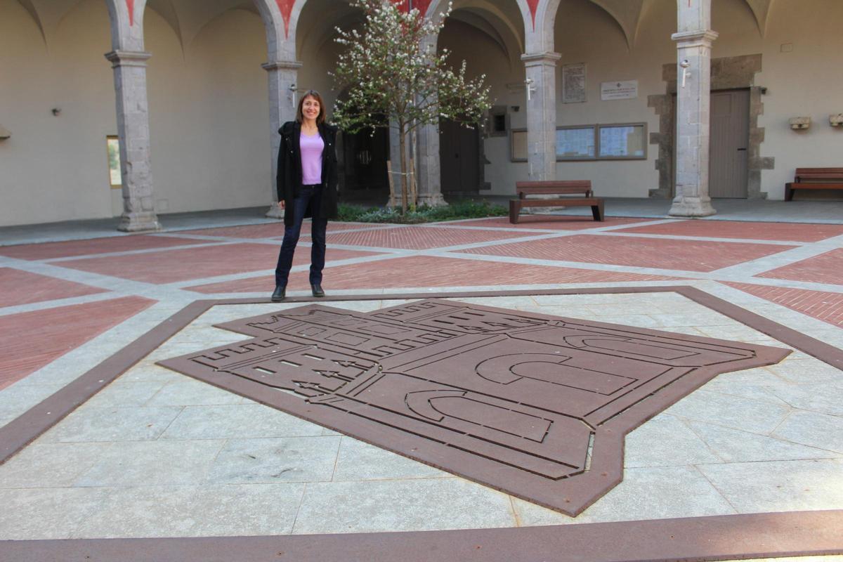 L'alcaldessa de Castelló davant l'escut de la vila a la plaça del palau dels Comtes