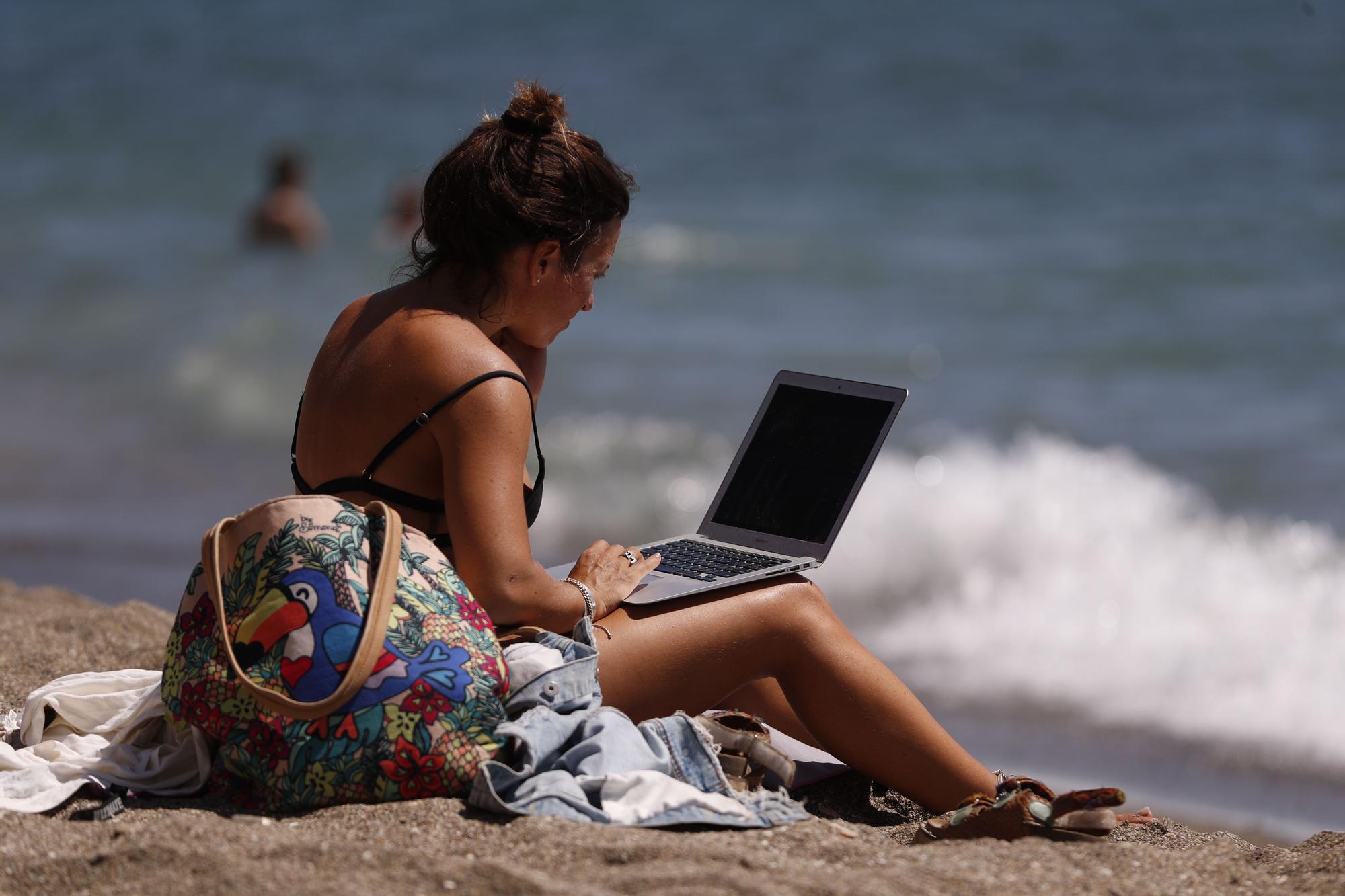 Consulta el portatil en la playa el pasado octubre, con récord en los termómetros.