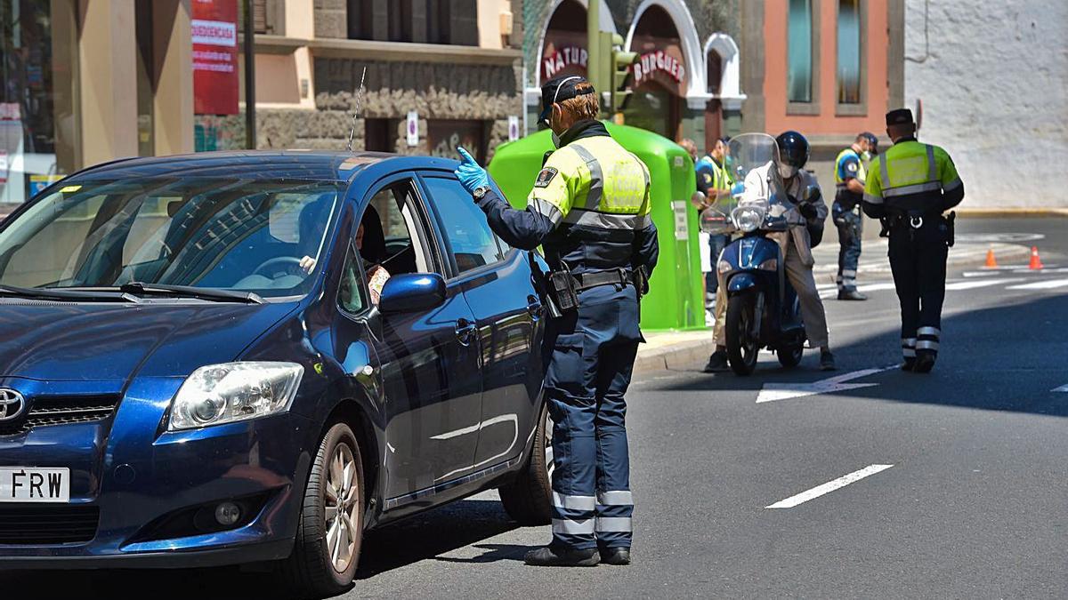 Varios agentes de policía supervisan la documentación de varios vehículos.