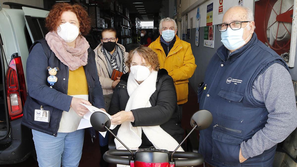 Ana Estévez, en su nueva moto adaptada, entrega ayer en el Banco de Alimentos de Vigo el dinero recaudado