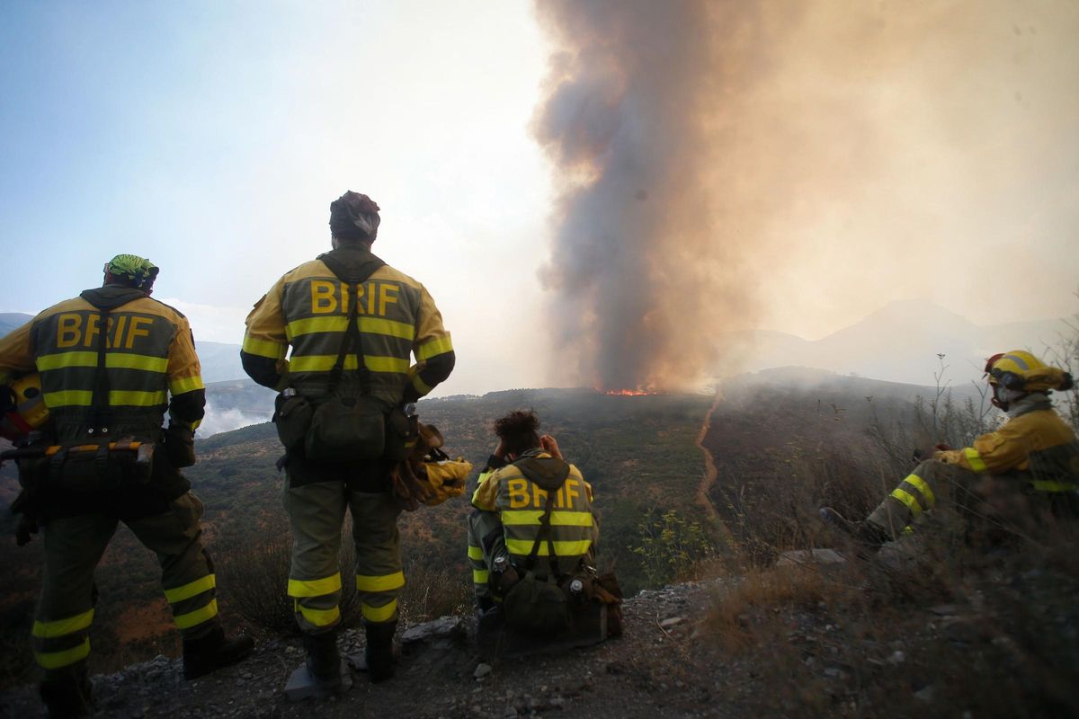 Varios bomberos observan el incendio forestal en La Baña, León, procedente de Porto. Varios bomberos observan el incendio forestal en La Baña, León, procedente de Porto.
