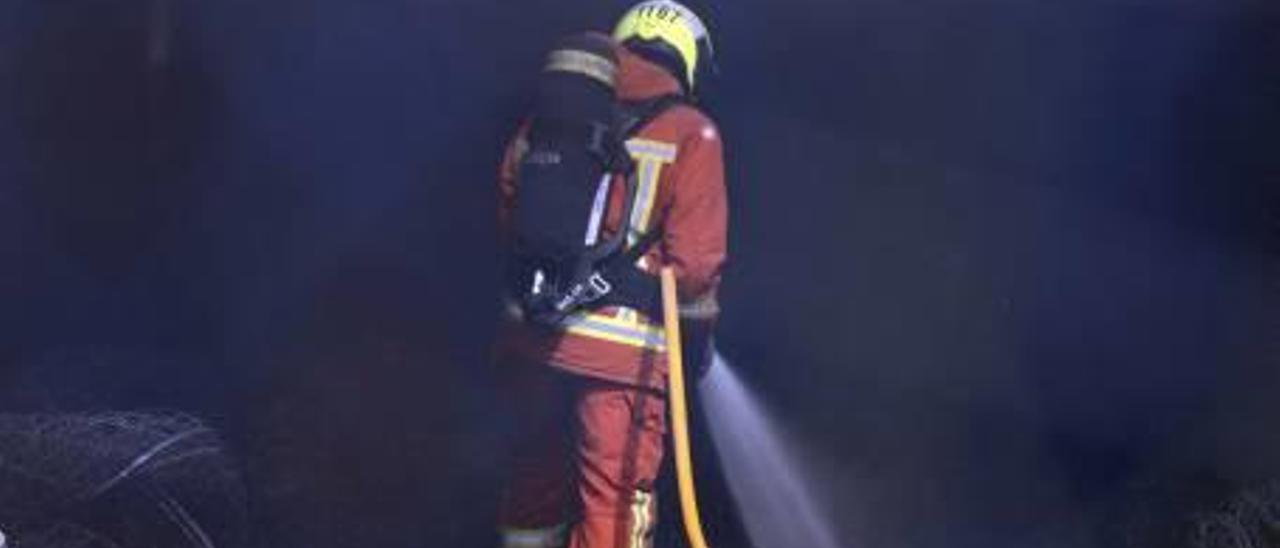Un bombero refresca la zona afectada por el incendio.