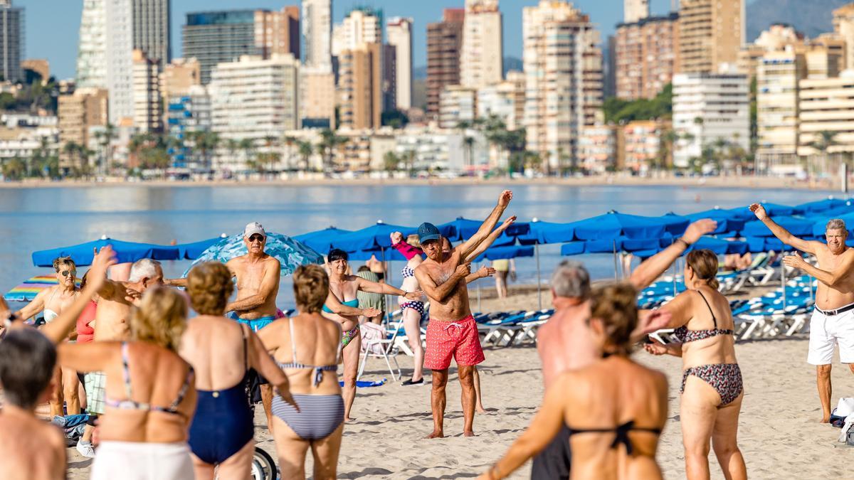 Un grupo de personas mayores haciendo ejercicio en la misma playa de Benidorm.