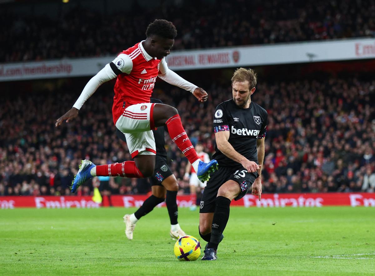 Saka salta sobre el balón que intenta despejar Dawson en el Arsenal-West Ham.