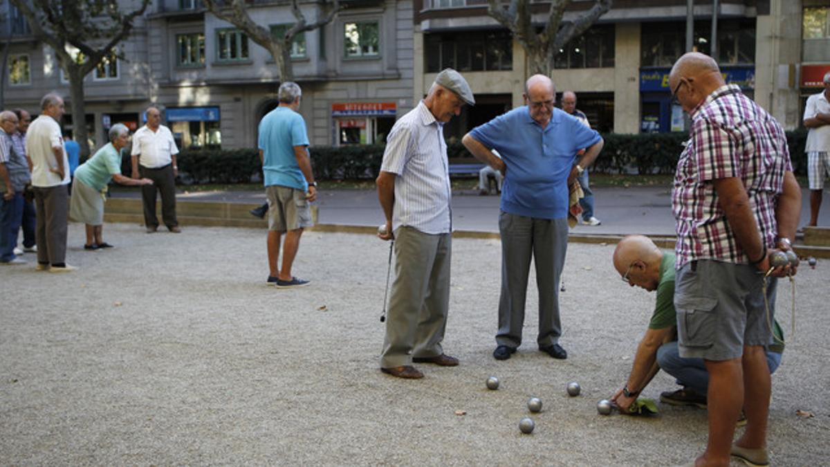 Un grupo de jubilados juega a la petanca en el Paseo de Sant Joan, en Barcelona.