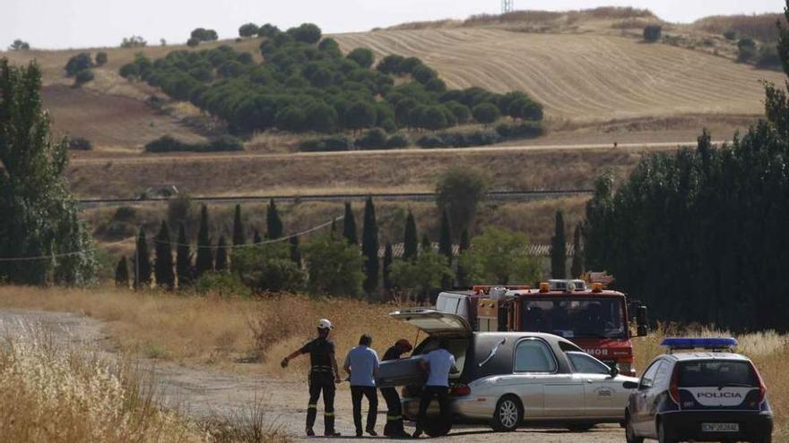 Los bomberos trasladan al coche fúnebre el cuerpo del pastor fallecido.