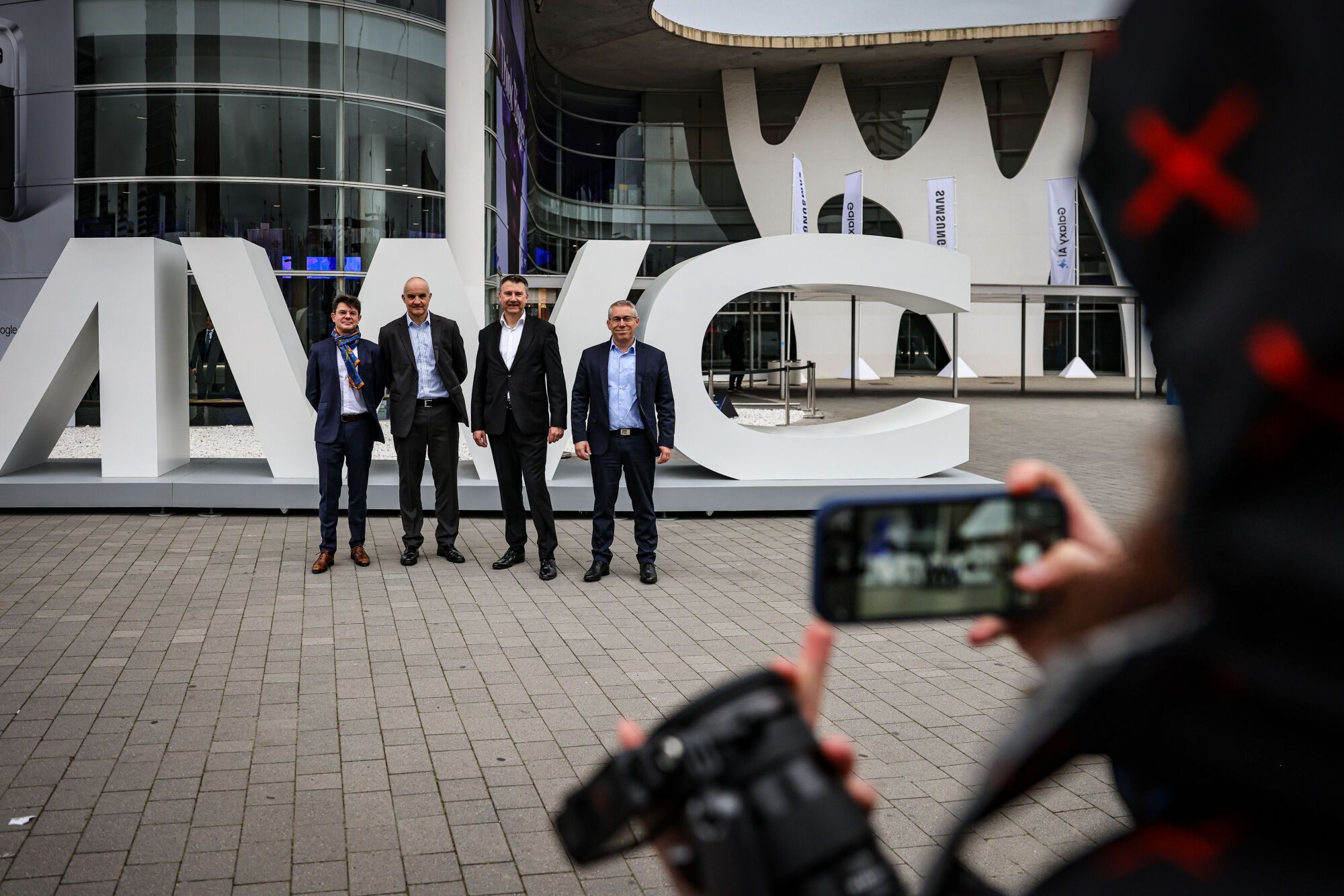 Un grup d’homes es fa una fotografia a l’entrada del MWC25