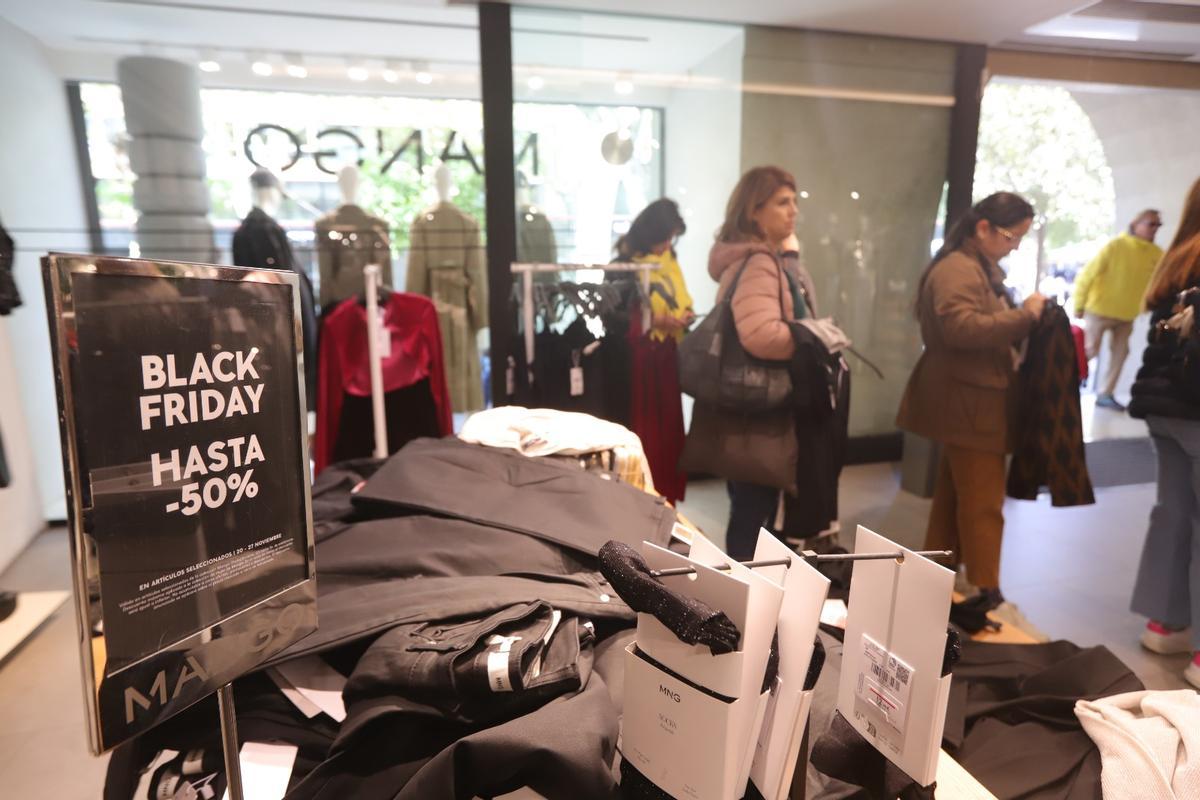 Varias clientas cargan ropa en una tienda con ofertas por el Black Friday.