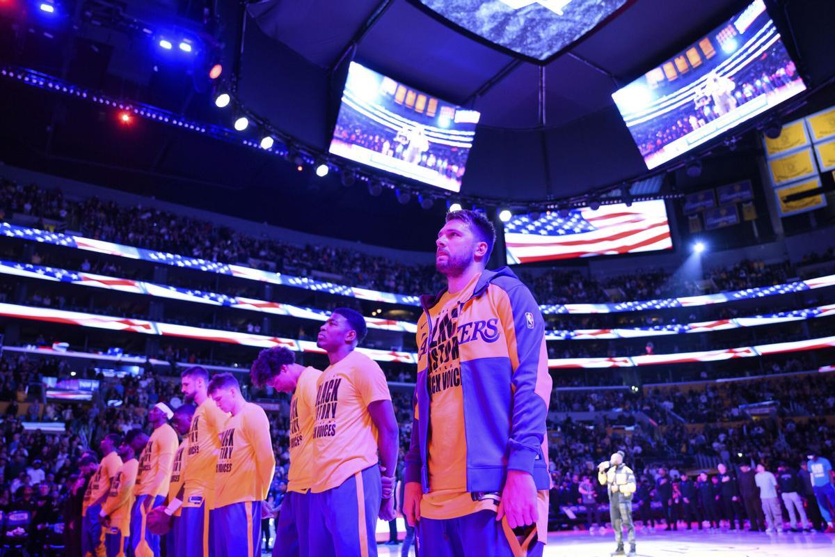 Los Angeles Lakers guard Luka Doncic, right, looks on during the national anthem before an NBA basketball game Wednesday, Feb. 19, 2025, in Los Angeles. (AP Photo/William Liang)