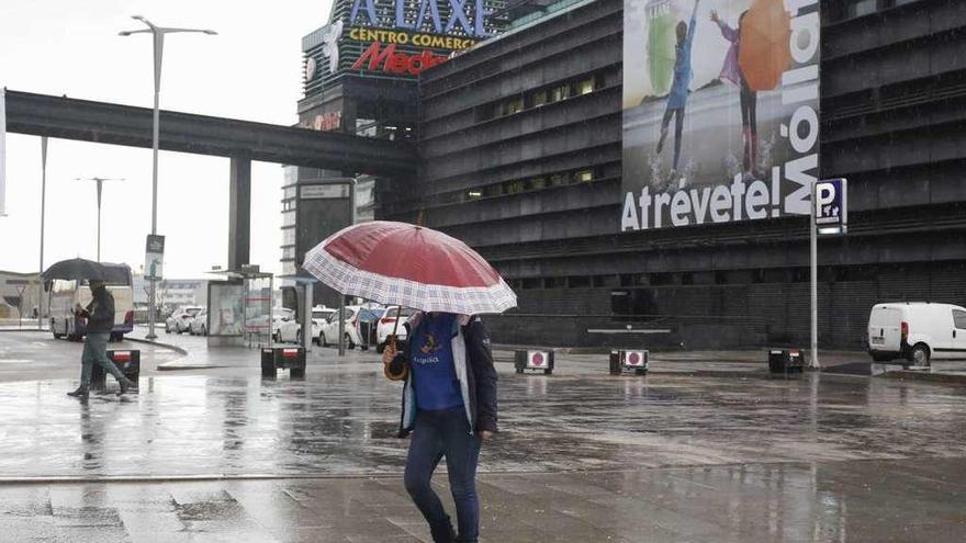 Una mujer pasea resguardándose de la lluvia que cayó ayer. // Cristina Graña