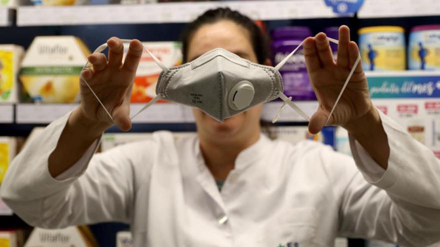 Una farmacéutica muestra una mascarilla para prevenir el contagio del coronavirus