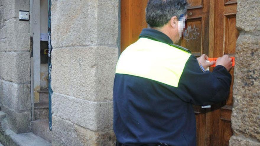 Un agente de la Policía Local coloca un precinto en un bar del casco viejo.  // Rafa Vázquez