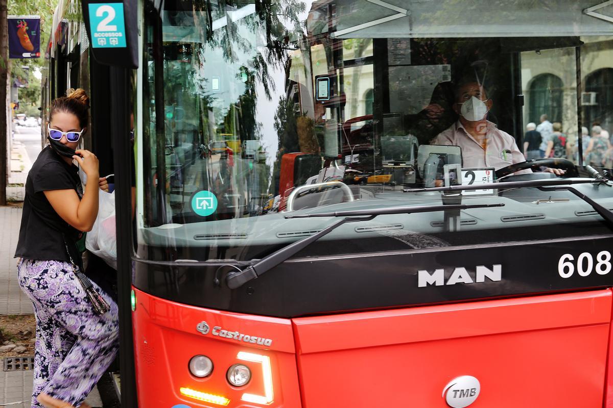 Una joven se coloca la mascarilla para entrar en un bus de TMB, en Barcelona