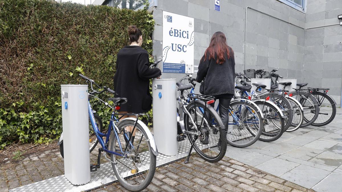 Dúas universitarias observan as bicicletas depositadas na estación da biblioteca Concepción Arenal, a que rexistra maior movemento