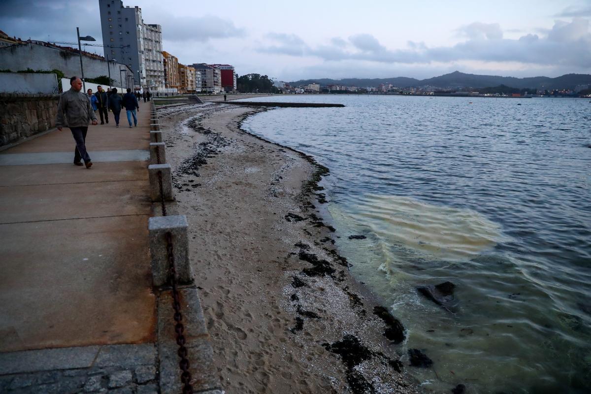 Un viandante contempla la mancha de combustible en la playa de Compostela