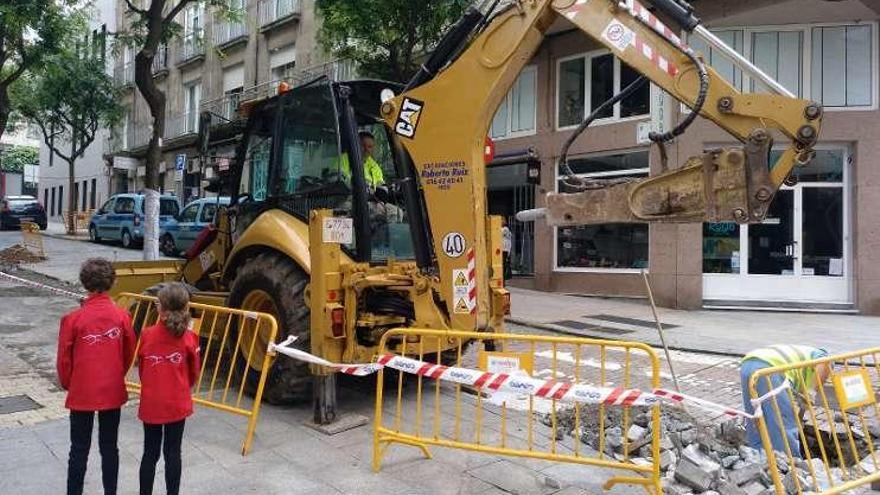 Dos menores observan el trabajo de una pala junto a un árbol con el tronco precintado ayer en María Berdiales. // FdV